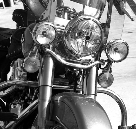three headlights of a large classic motorbike with metal chrome, parked, black and white photo