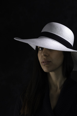 portrait of a beautiful young girl with a white hat on a black background,  looking at the cameraのeditorial素材
