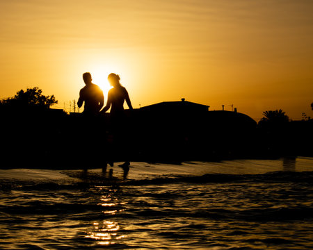 Beautiful backlighting sunset with a couple walking on the beachの写真素材