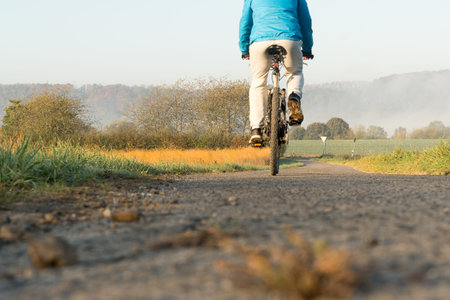 Cyclist riding a bicycle on the country road in autumn.