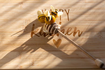 3 marzipan bees on a honey spoon on the kitchen table.の写真素材