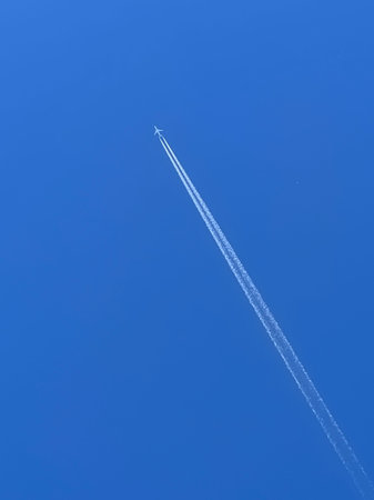 Plane in the sky with condensation trails.