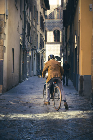 Old man riding a bicycle in the old city, Italy.