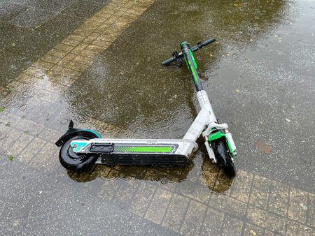 Electric scooter abandoned in water in puddle.