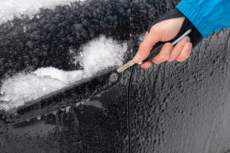Man's hand with a wrench repairing a car covered with snow.