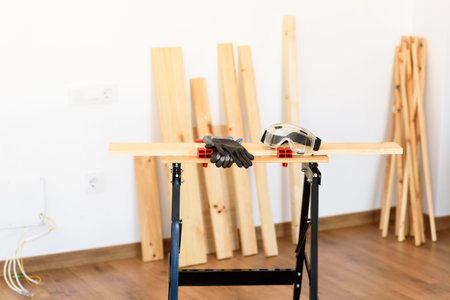 Workbench with protective glasses and safety gloves, without anyone. Inside a flat with wooden...