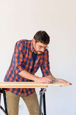 Man at home sanding a wood on a workbench. White background.の写真素材
