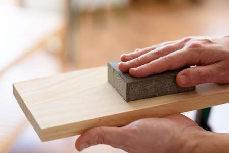 Close up shot of a man at home sanding wood on a workbench. High quality photo.の写真素材