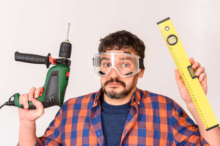 DIY enthusiast man holds a drill. White background. Plain shirt.の写真素材