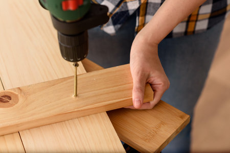 DIY enthusiast man holds a drill. White background. Plain shirt.