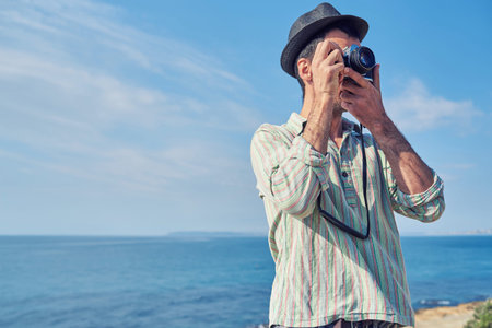 A man on vacation takes photos with a vintage camera in a beach resortの写真素材
