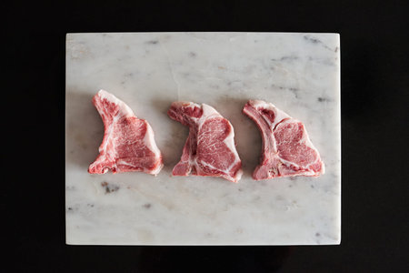 Raw Iberian pork chops on a white marble table