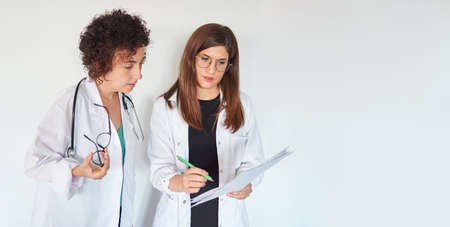 Two female doctors look at documents and discuss a diagnosisの写真素材