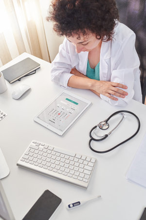 High angle shot of a female doctor consulting the calendar on her tablet