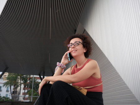 Curly-haired Caucasian woman talking on cell phone in downtown area