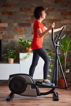 Woman training at home using elliptical cross trainer
