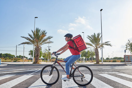 Food delivery woman riding bicycle in cityの写真素材