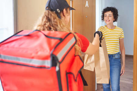 A delivery woman delivers a food order to a customerの写真素材