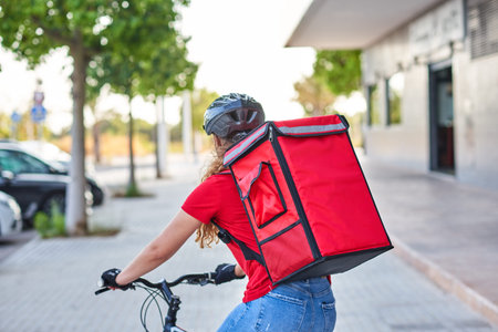 Unrecognizable food delivery woman riding bicycle in city