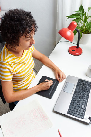 Graphic designer working from home with a graphic tablet and laptop