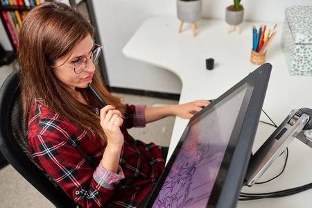 Caucasian female artist illustrator painting drawing on touch digital tablet with stylusの写真素材