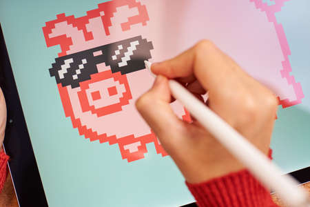 Female artist painting digitally on a tablet creating NFTの写真素材