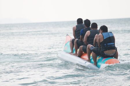 Young people enjoying a ride on a banana boatの写真素材