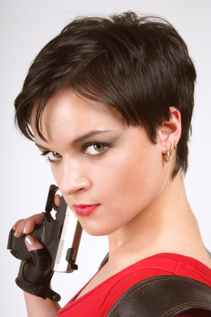 Beautiful dark-haired girl in leather gloves with pistol and pistol holsterの写真素材