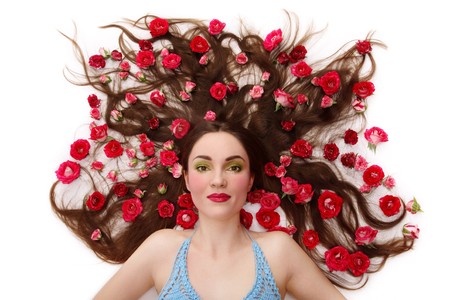 Beautiful girl lying on white background with pink roses in her long hairの写真素材