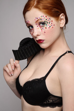 Beautiful redhead girl with fancy makeup in sexy black bra