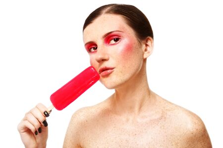 Beautiful young freckled girl with stylish make-up and red fruit ice on white backgroundの写真素材