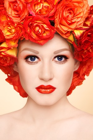 Young beautiful sexy girl with stylish orange make-up and colorful flowers around her faceの写真素材
