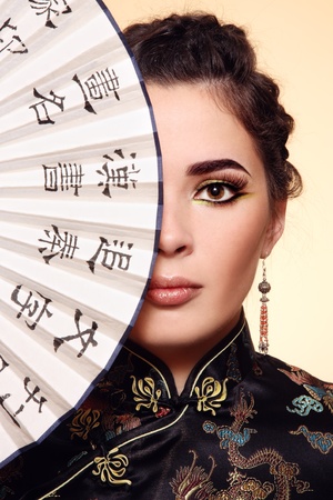 Close-up portrait of young beautiful woman with Chinese fanの写真素材