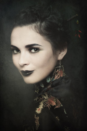 Duotone colored portrait of young beautiful woman in Chinese costume on vintage damaged grainy backgroundの写真素材