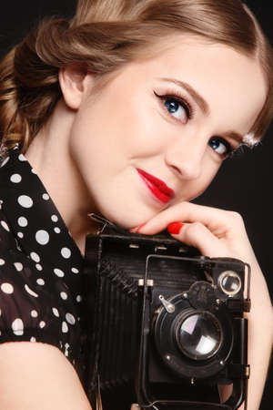 Young beautiful smiling blond girl with old camera in handsの写真素材