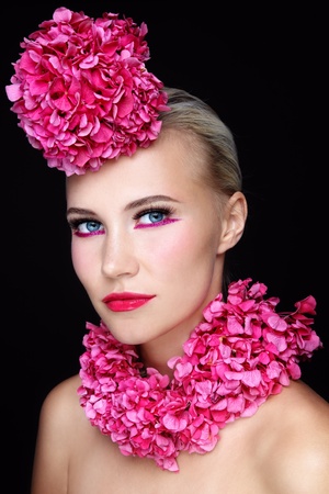 Portrait of young beautiful girl with stylish sparkly pink make-up and flowers on her head and neckの写真素材