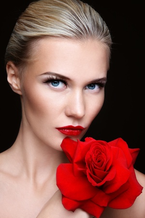 Close-up portrait of young beautiful sexy blond woman with red roseの写真素材