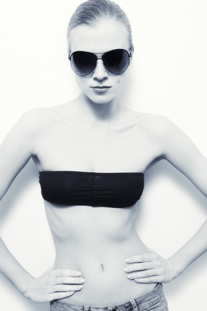 Young slim model in stylish sunglasses over white wallの写真素材