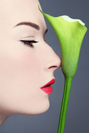 Profile portrait of young beautiful woman with fancy green flowerの写真素材