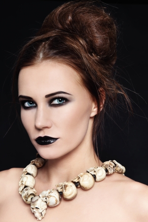 Portrait of young beautiful woman with black lipstick and gothic skull necklaceの写真素材