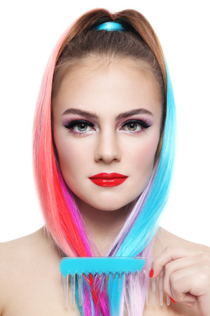 Portrait of young beautiful smiling girl with colorful ponytail and comb in her handの写真素材