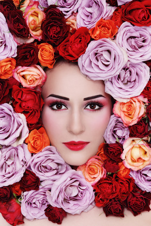 Portrait of young beautiful woman with colorful roses around her faceの写真素材