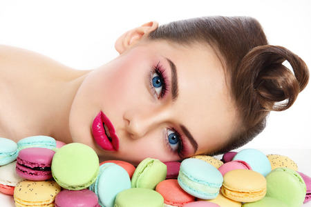 Portrait of young beautiful woman with colorful macaroons over white の写真素材