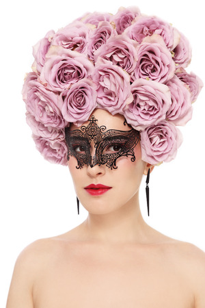 Portrait of young beautiful woman with fancy flower wig and venetian mask over white の写真素材