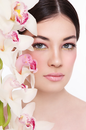 Close-up portrait of young beautiful woman with white orchidの写真素材