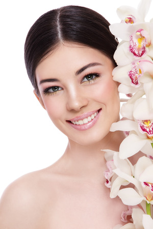 Young beautiful healthy smiling happy woman with white orchid over white backgroundの写真素材
