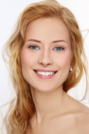 Portrait of young beautiful happy smiling girl with curly hair and clean make-upの写真素材