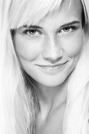 Black and white portrait of young beautiful healthy smiling blonde girl with frecklesの写真素材
