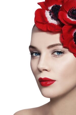 Portrait of young beautiful woman with clean make-up, red lips and red flowers in her hair over white background, copy spaceの写真素材