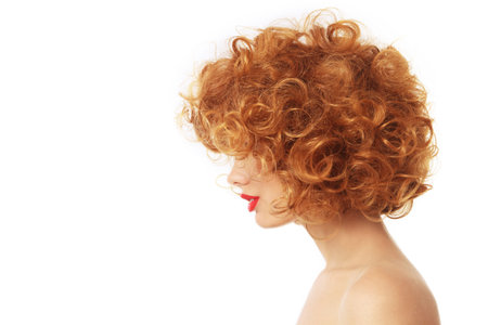 Profile portrait of young woman with beautiful red curly hair over wite backgroundの写真素材